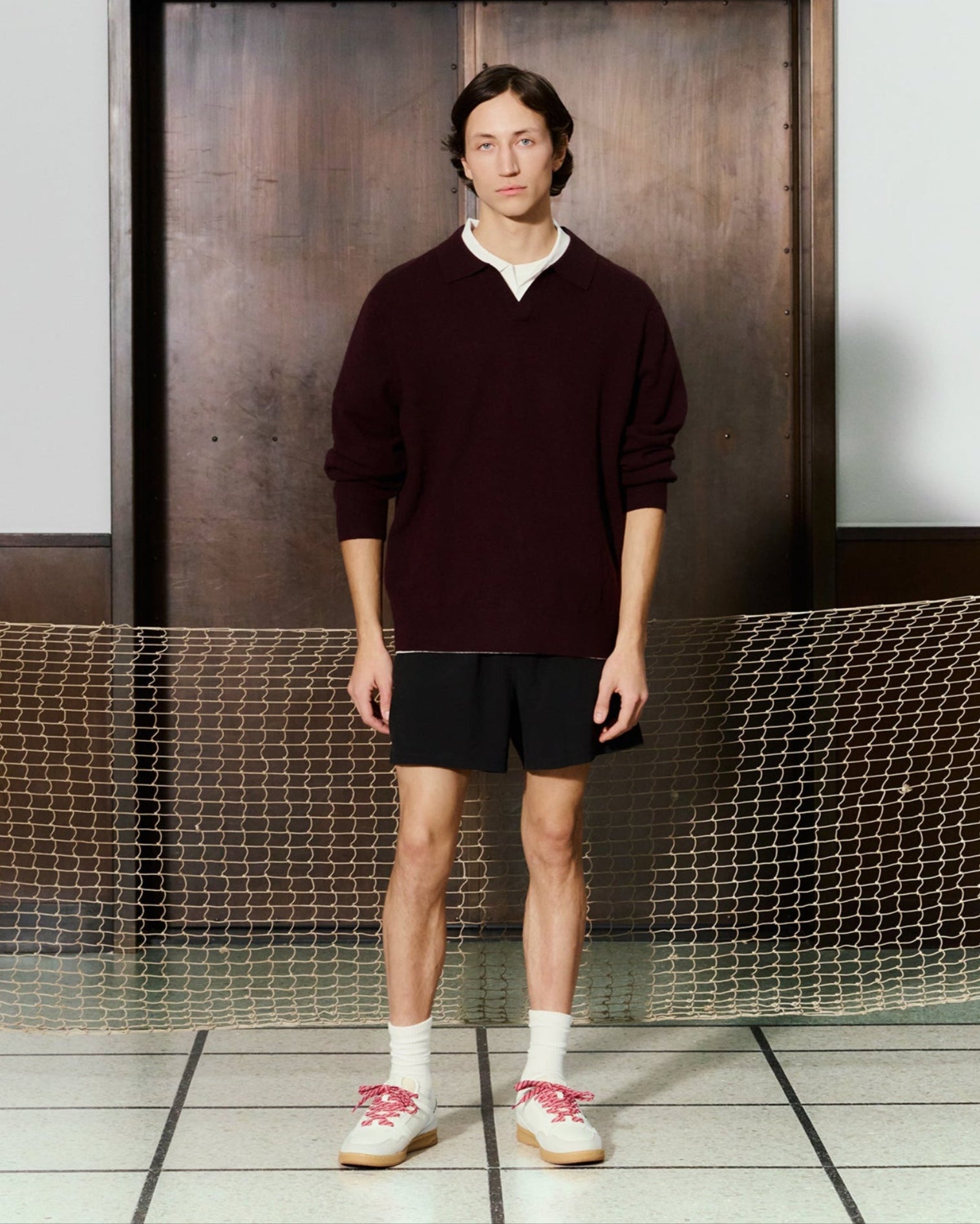 Lookbook shot inside Kunstmuseum – model wearing ACE 25 sneakers with red laces, styled in tennis-inspired outfit