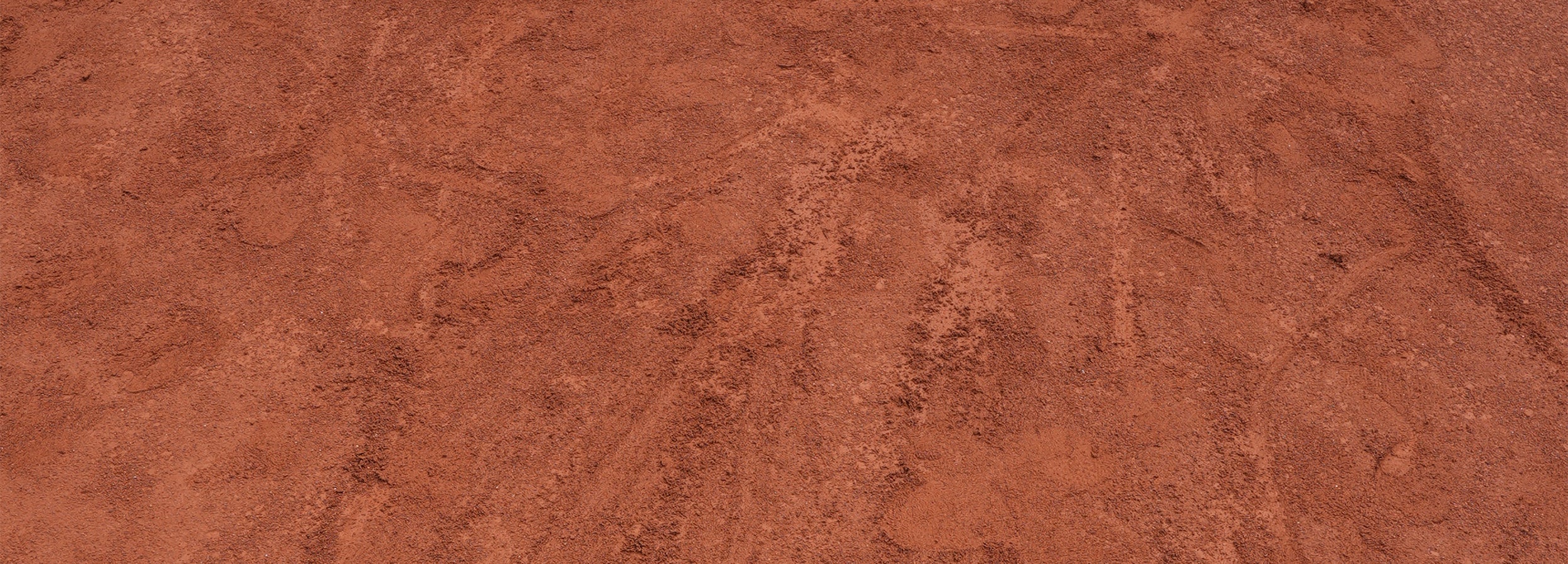 Gravel tennis court surface close-up – textured red clay used in traditional European tennis matches

