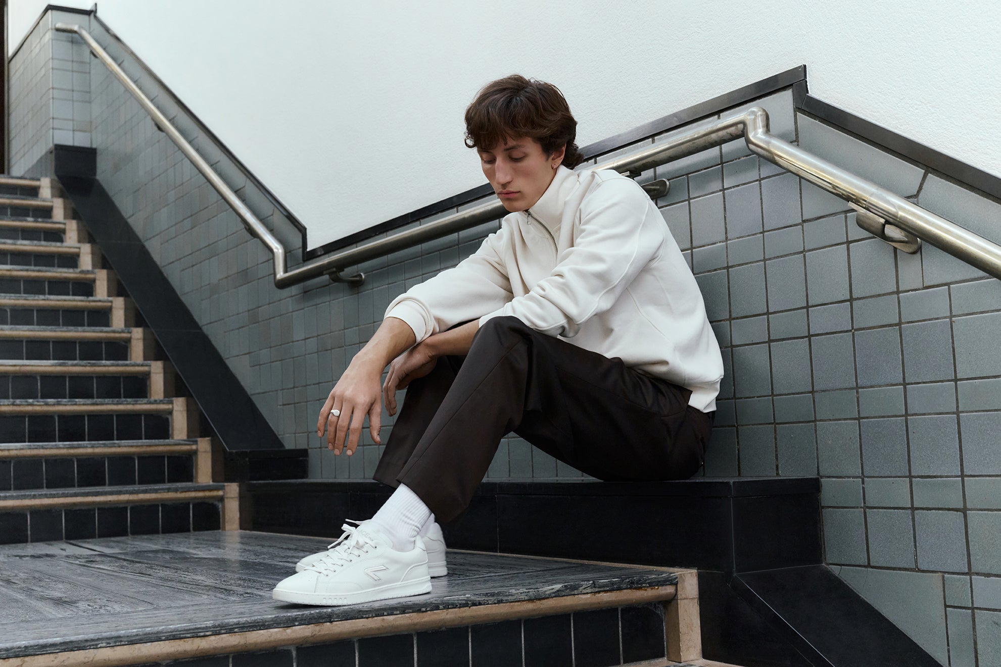 The ACE Hub Sprint sneaker in off-white, worn in tiled stairwell at The Hague art museum
